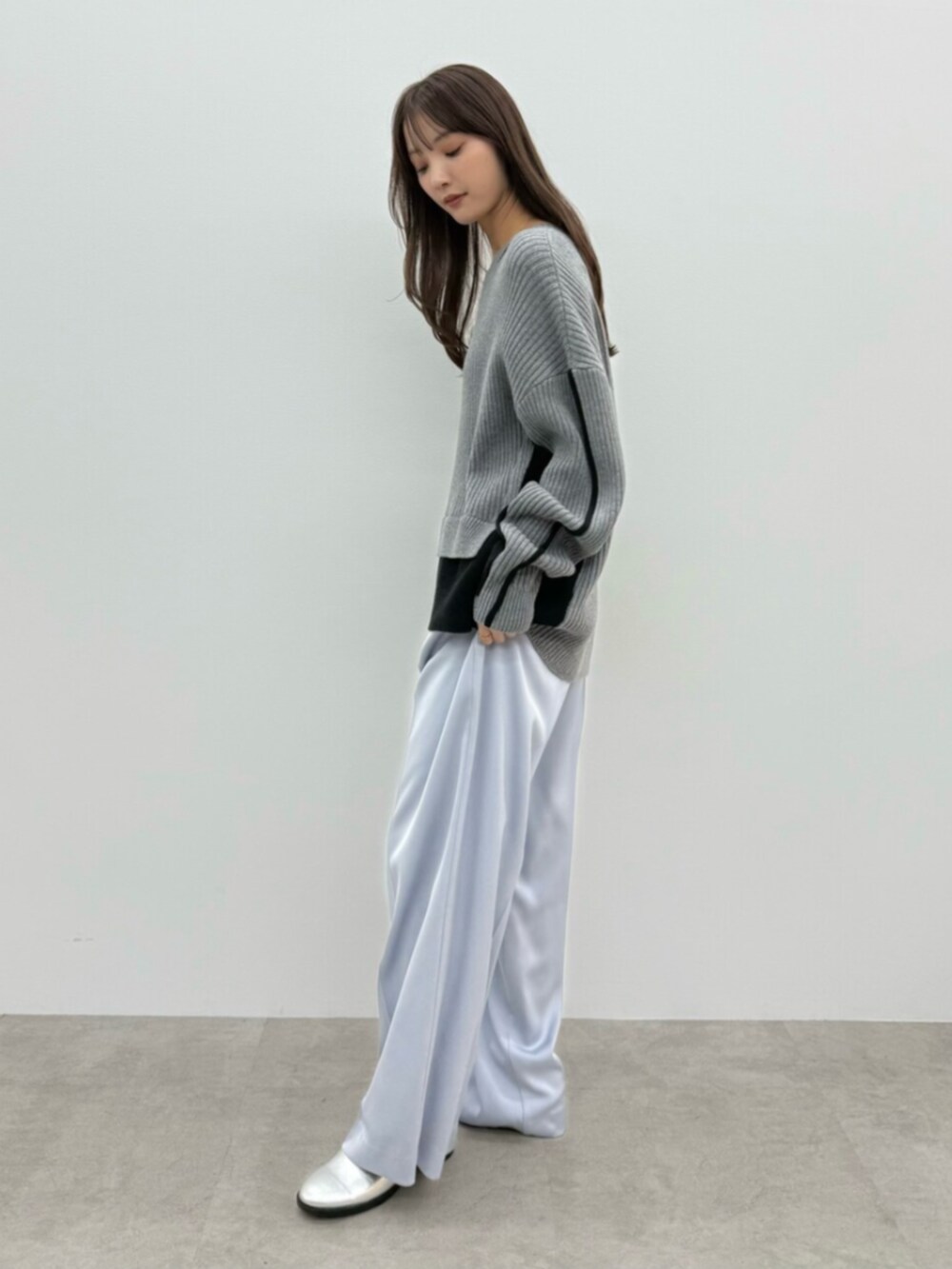 グレー系のニット/セーター、ブルー系のその他パンツ、シルバー系のパンプスを着用したレディースの秋コーディネートの2枚目の写真