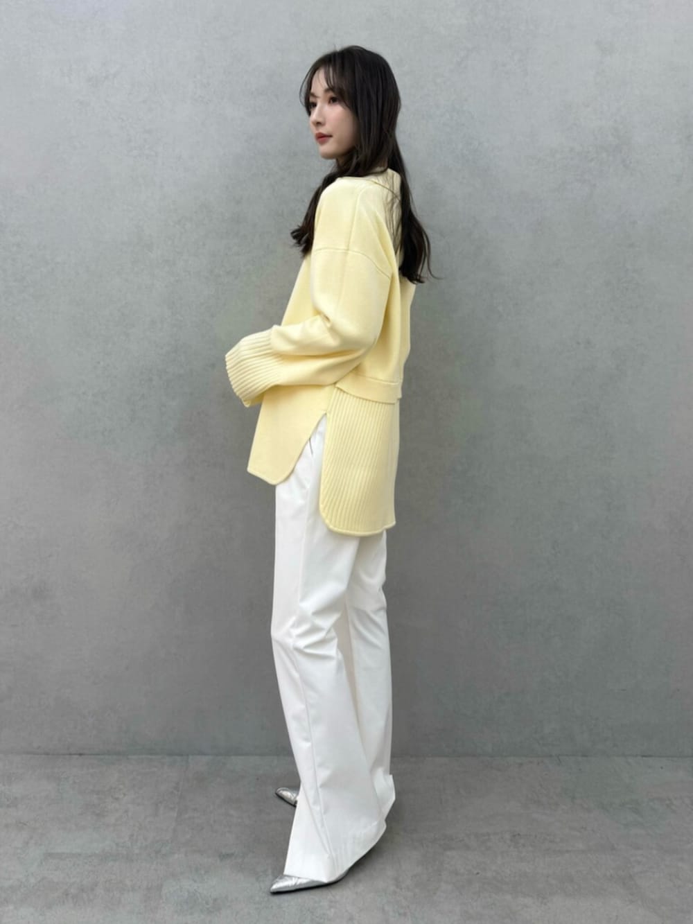 イエロー系のニット/セーター、ホワイト系のその他パンツ、ホワイト系のキャミソールを着用したレディースの冬コーディネートの2枚目の写真
