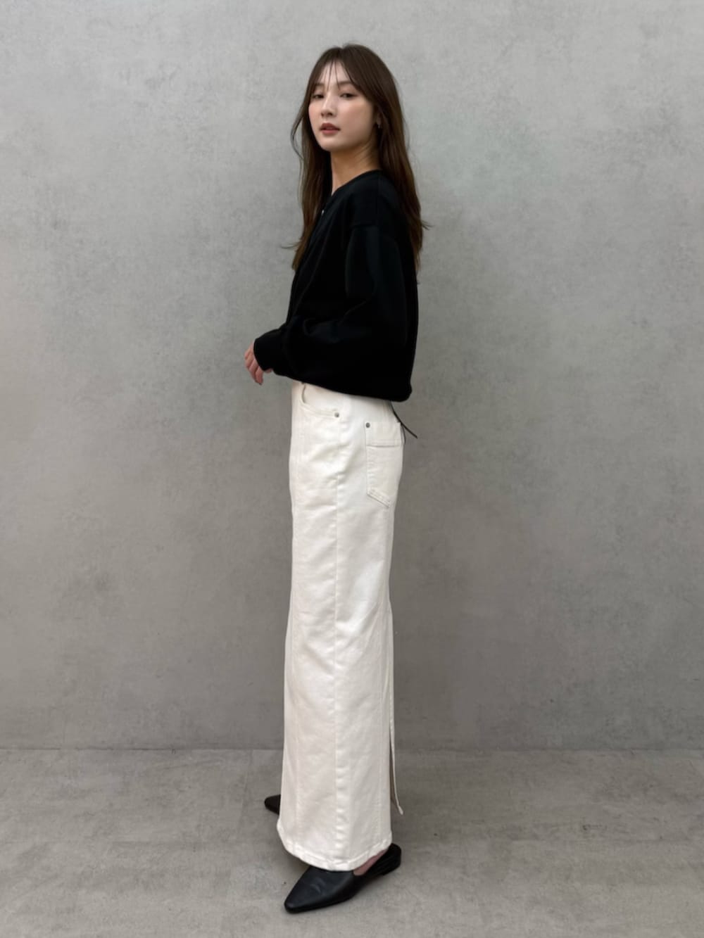 ブラック系のカーディガン/ボレロ、ブラック系のパンプス、ホワイト系のスカートを着用したレディースの春コーディネートの2枚目の写真