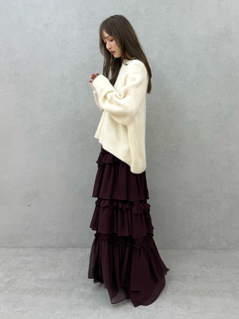 ホワイト系のチェスターコート、ホワイト系のニット/セーター、レッド系のスカートを着用したレディースの秋コーディネートの6枚目の写真