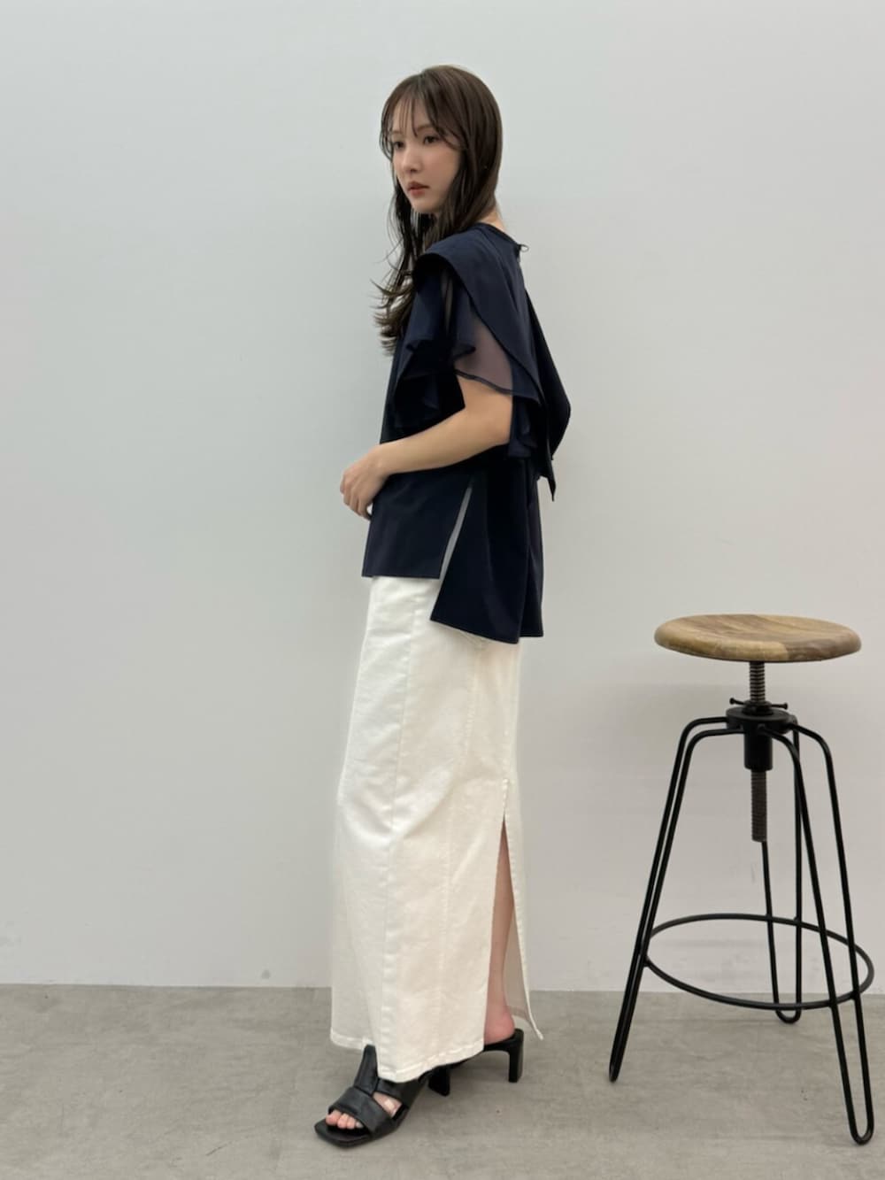 ブルー系のシャツ/ブラウス、ホワイト系のスカート、ブラック系のサンダルを着用したレディースの春コーディネートの2枚目の写真