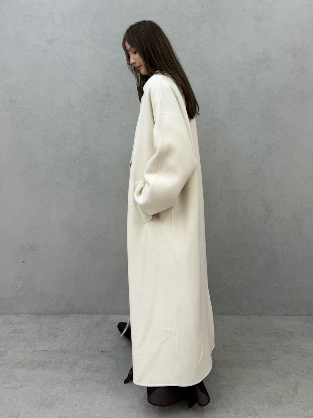 ホワイト系のチェスターコート、ホワイト系のニット/セーター、レッド系のスカートを着用したレディースの秋コーディネートの3枚目の写真