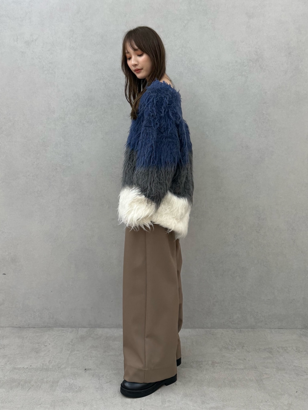 ブルー系のニット/セーター、ブラウン系のその他パンツを着用したレディースの秋コーディネートの3枚目の写真