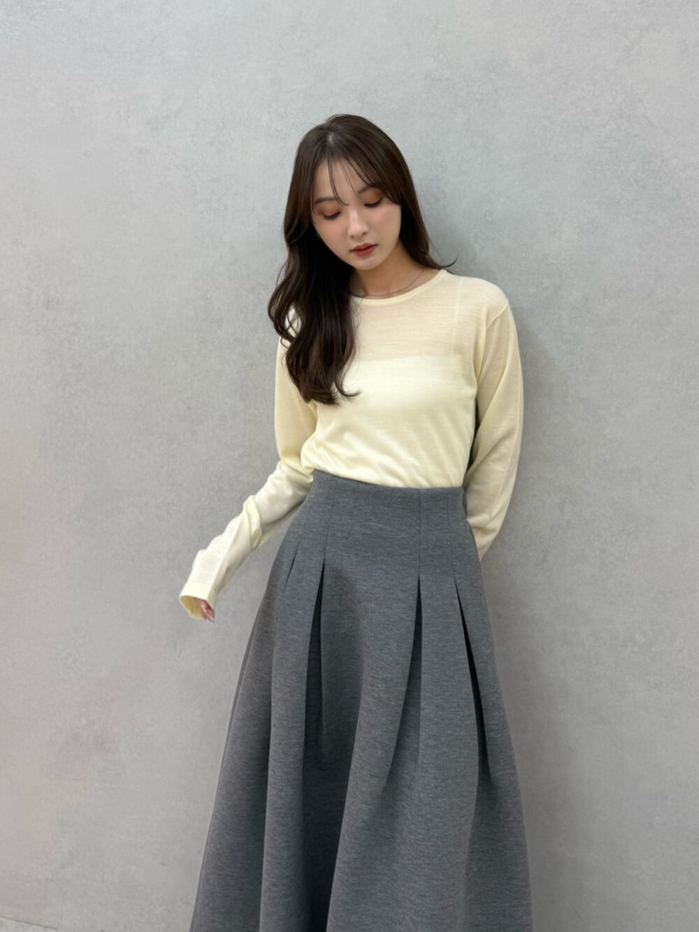 イエロー系のニット/セーター、グレー系のスカート、ブラック系のパンプスを着用したレディースの冬コーディネートの5枚目の写真