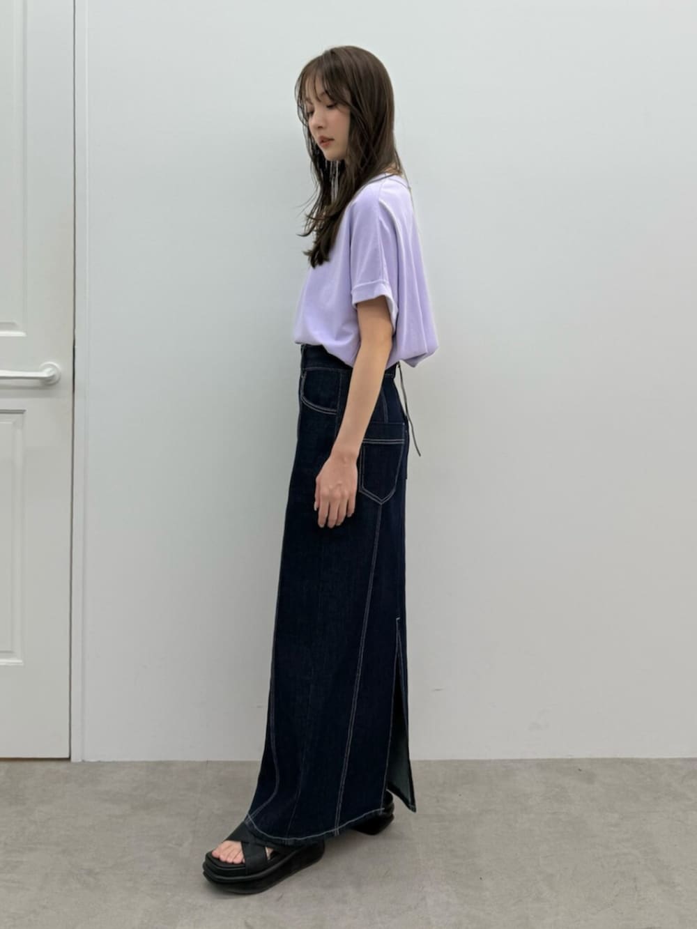 ブルー系のスカート、パープル系のTシャツ/カットソー、ブラック系のサンダルを着用したレディースの春コーディネートの3枚目の写真