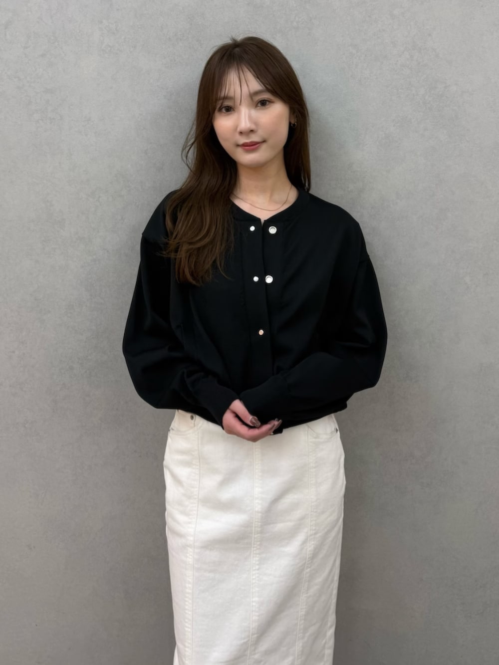 ブラック系のカーディガン/ボレロ、ブラック系のパンプス、ホワイト系のスカートを着用したレディースの春コーディネートの6枚目の写真