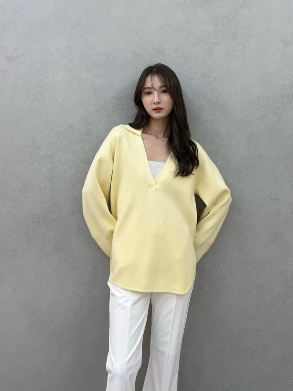 イエロー系のニット/セーター、ホワイト系のその他パンツ、ホワイト系のキャミソールを着用したレディースの冬コーディネートの6枚目の写真