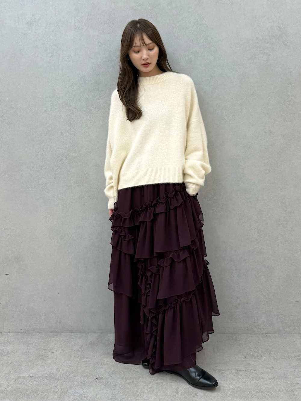 ホワイト系のチェスターコート、ホワイト系のニット/セーター、レッド系のスカートを着用したレディースの秋コーディネートの5枚目の写真