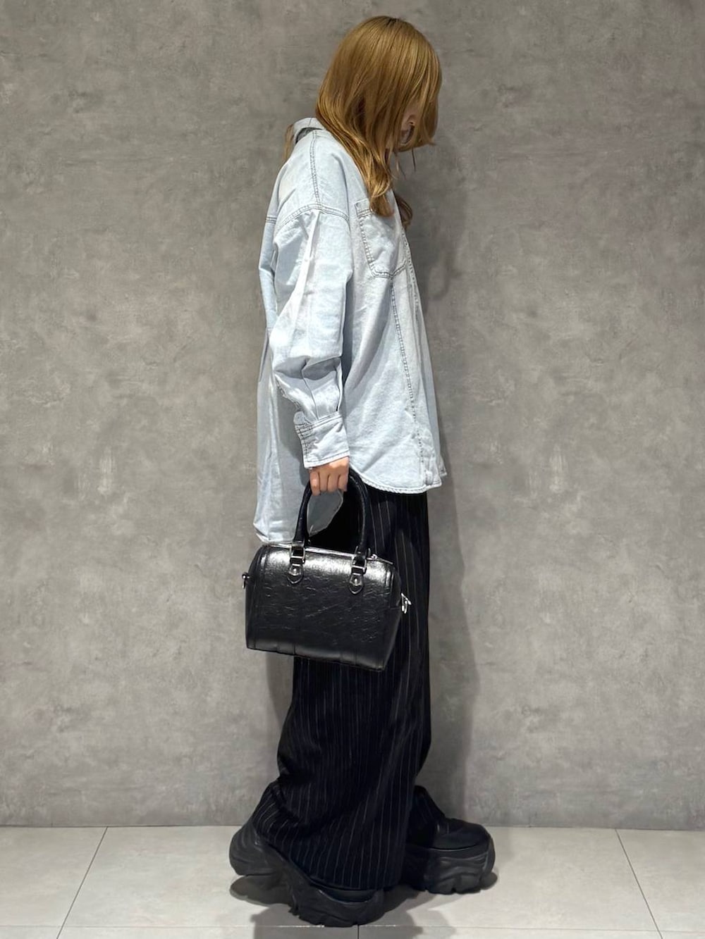 ブラック系のブーツ、ホワイト系のTシャツ/カットソー、ブラック系のボストンバッグを着用したレディースの冬コーディネートの4枚目の写真