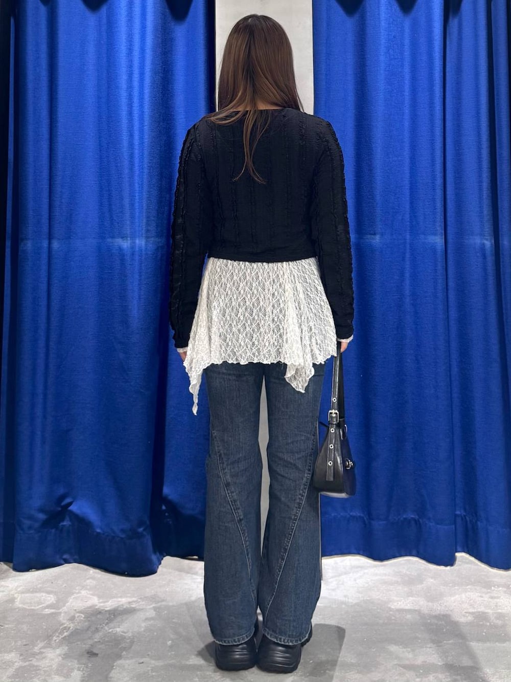 ブラック系のスニーカー、ブルー系のデニムパンツ、ホワイト系のチュニックを着用したレディースの春コーディネートの5枚目の写真