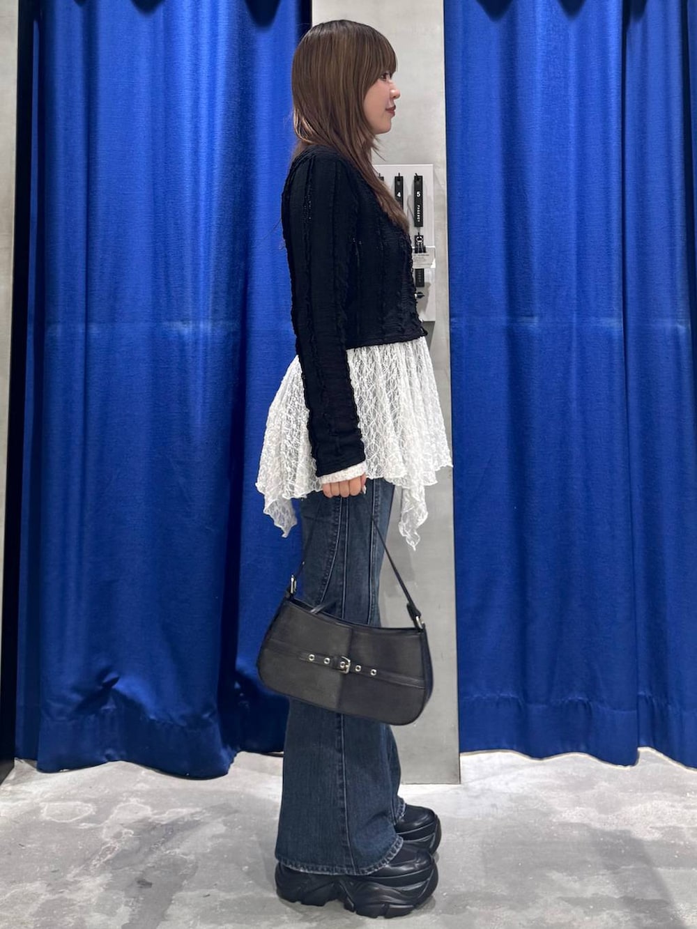 ブラック系のスニーカー、ブルー系のデニムパンツ、ホワイト系のチュニックを着用したレディースの春コーディネートの4枚目の写真
