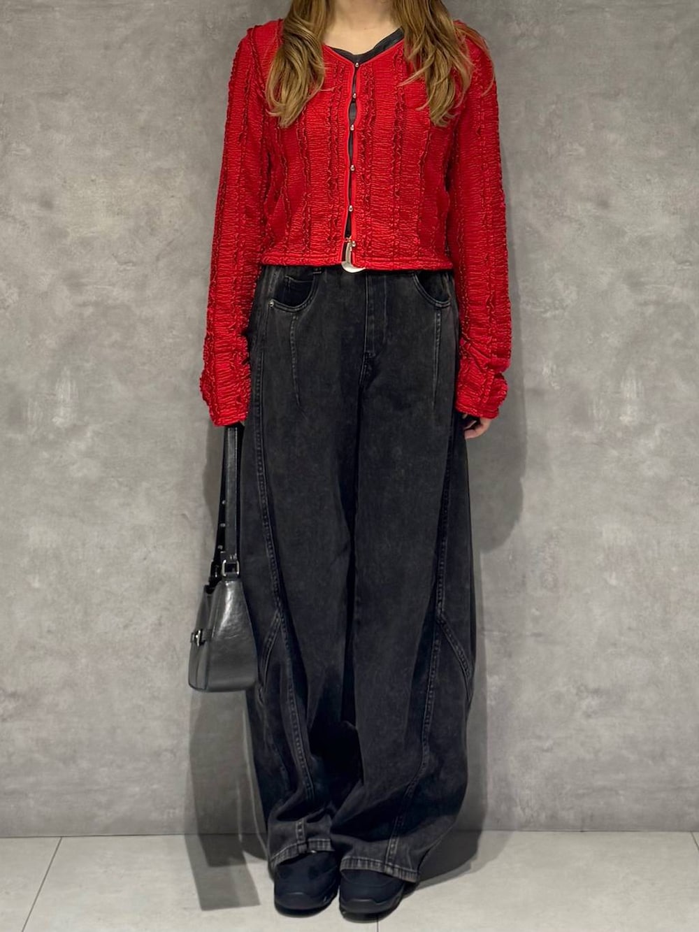 ブラック系のスニーカー、ブラック系のハンドバッグ、ブラック系のデニムパンツを着用したレディースの春コーディネートの2枚目の写真