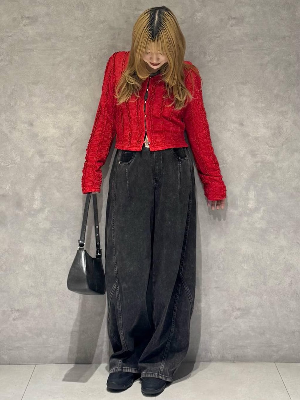 ブラック系のスニーカー、ブラック系のハンドバッグ、ブラック系のデニムパンツを着用したレディースの春コーディネートの3枚目の写真