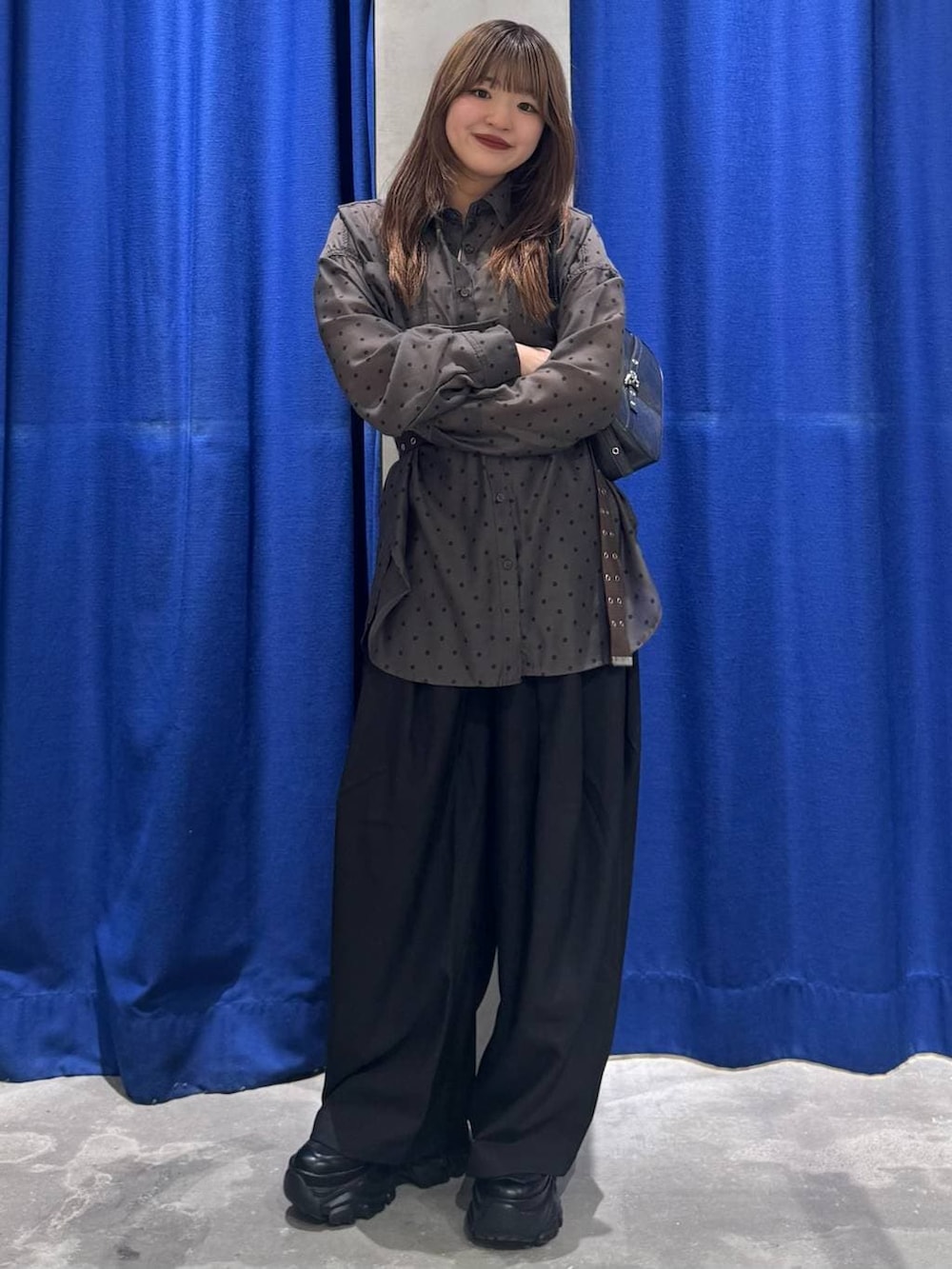 ブラック系のスニーカー、ブラック系のハンドバッグ、ブラック系のスラックスを着用したレディースの春コーディネートの7枚目の写真