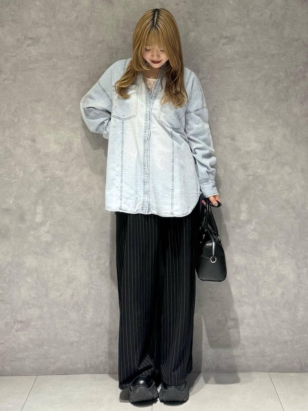 ブラック系のブーツ、ホワイト系のTシャツ/カットソー、ブラック系のボストンバッグを着用したレディースの冬コーディネートの3枚目の写真