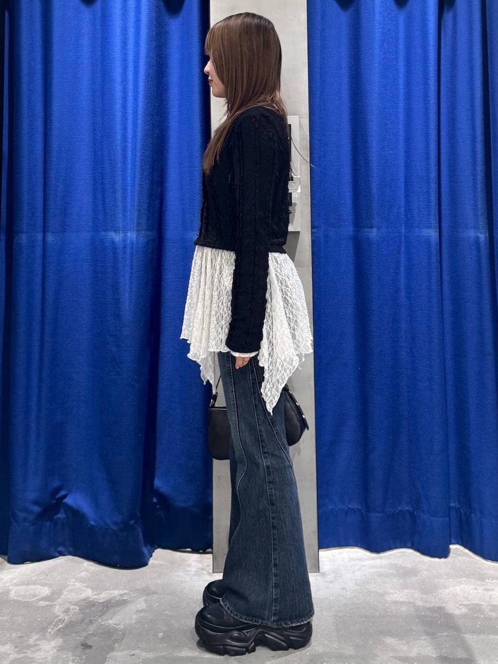 ブラック系のスニーカー、ブルー系のデニムパンツ、ホワイト系のチュニックを着用したレディースの春コーディネートの6枚目の写真