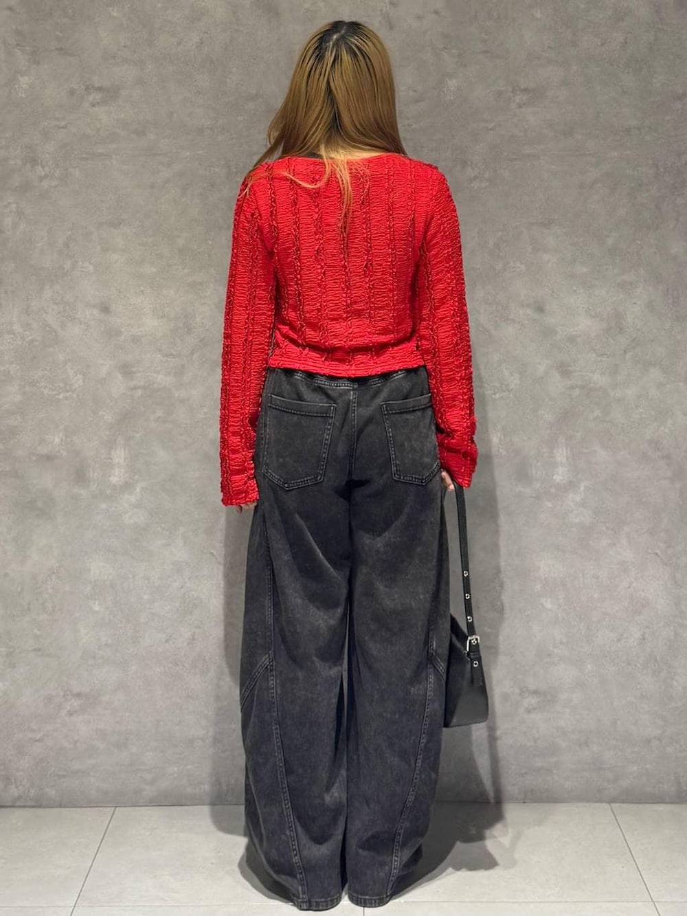 ブラック系のスニーカー、ブラック系のハンドバッグ、ブラック系のデニムパンツを着用したレディースの春コーディネートの5枚目の写真