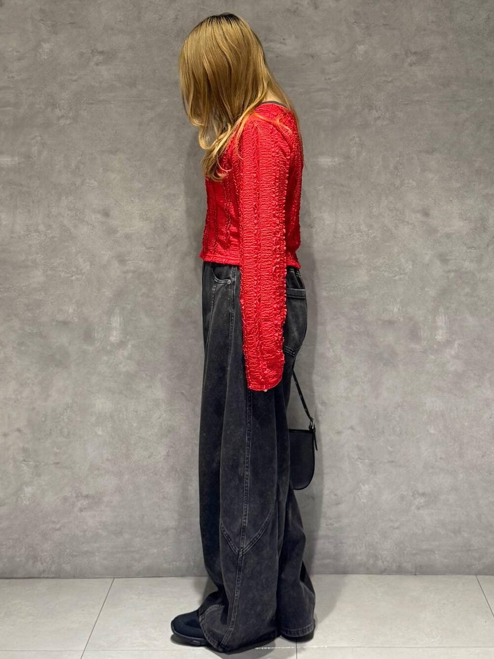 ブラック系のスニーカー、ブラック系のハンドバッグ、ブラック系のデニムパンツを着用したレディースの春コーディネートの6枚目の写真