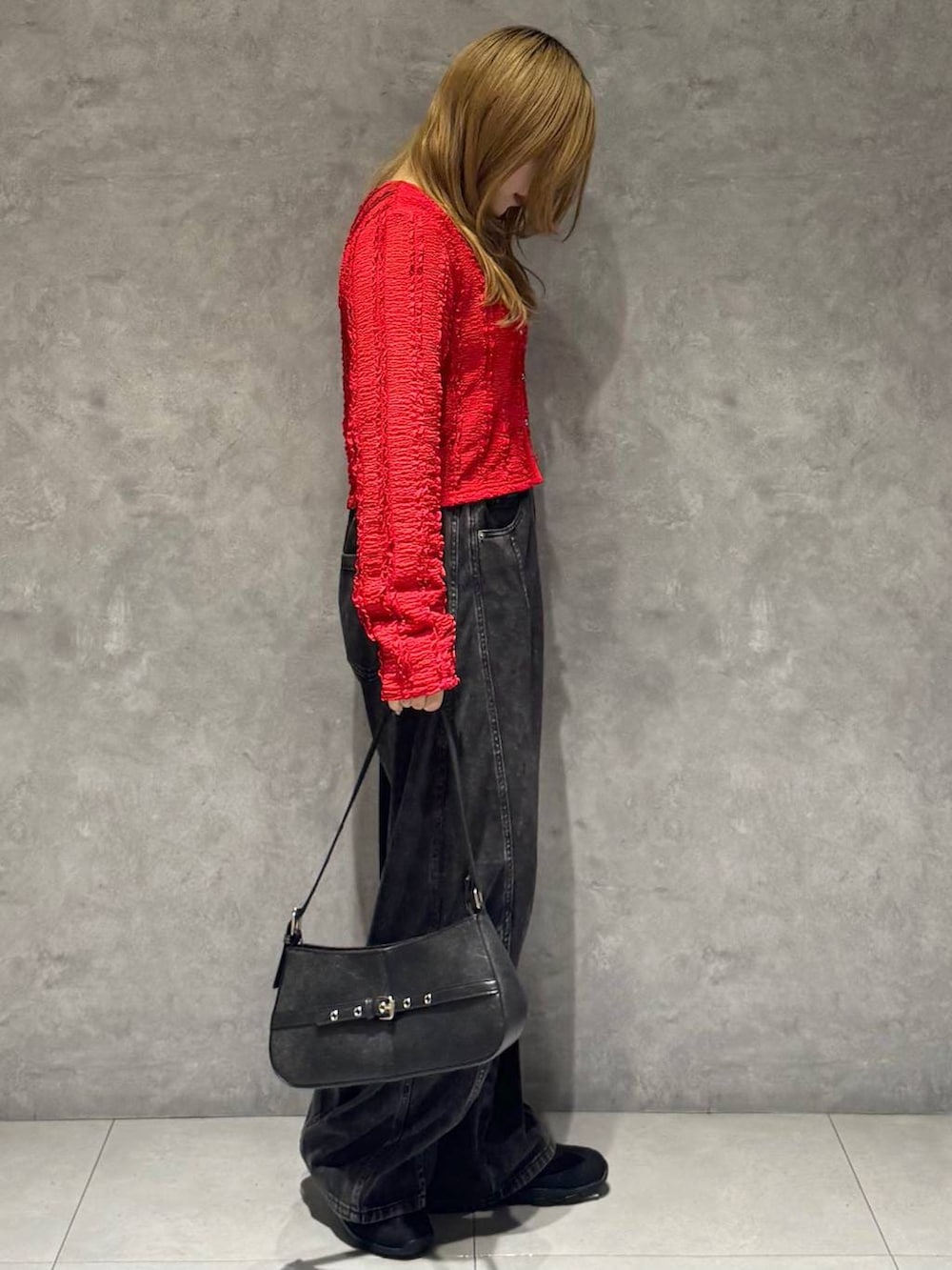 ブラック系のスニーカー、ブラック系のハンドバッグ、ブラック系のデニムパンツを着用したレディースの春コーディネートの4枚目の写真