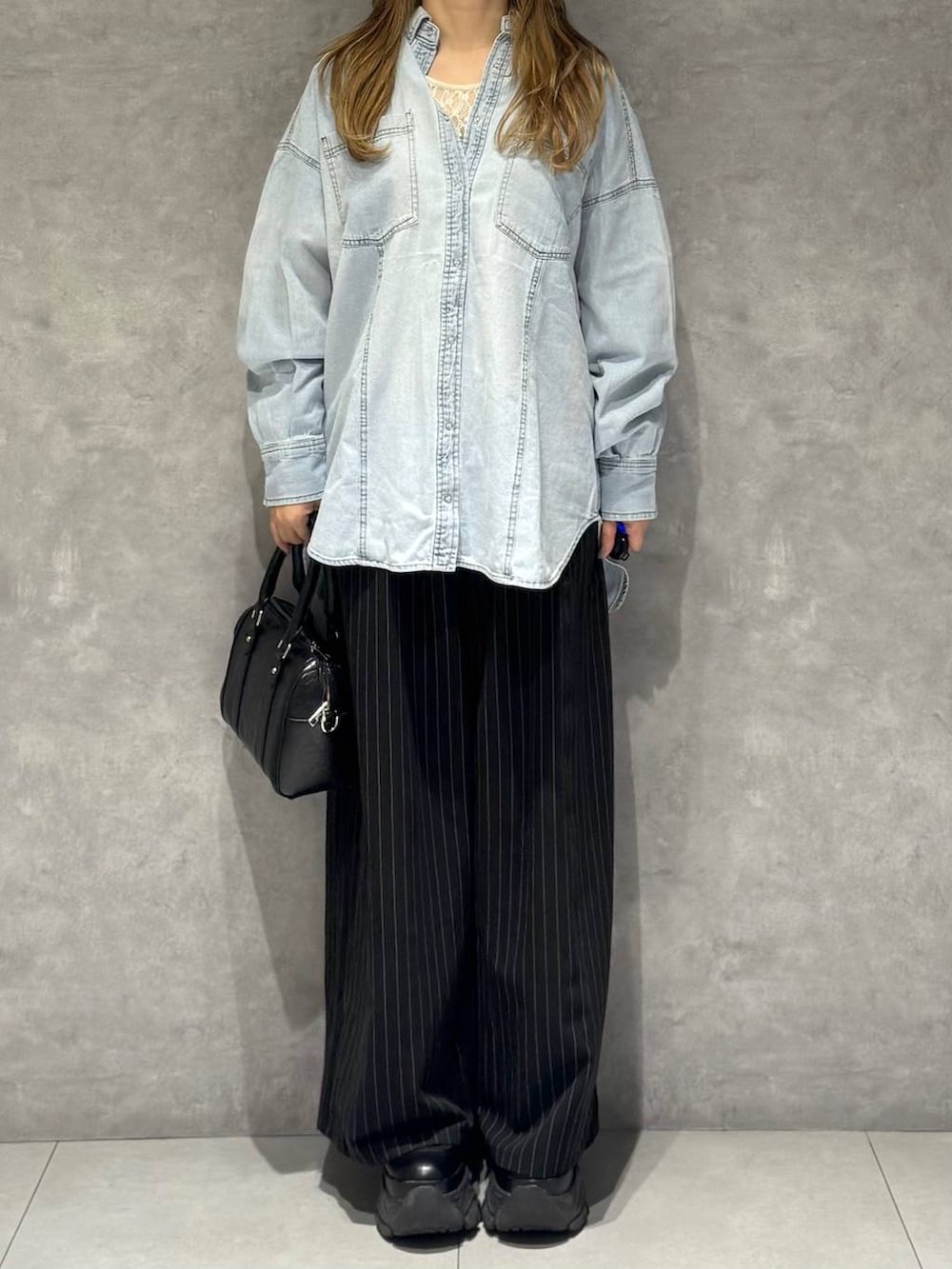 ブラック系のブーツ、ホワイト系のTシャツ/カットソー、ブラック系のボストンバッグを着用したレディースの冬コーディネートの2枚目の写真