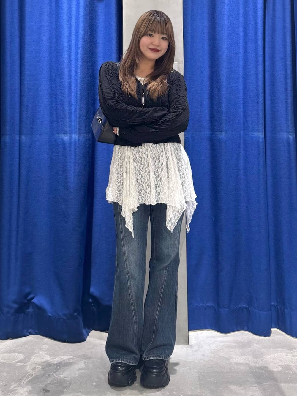 ブラック系のスニーカー、ブルー系のデニムパンツ、ホワイト系のチュニックを着用したレディースの春コーディネートの3枚目の写真