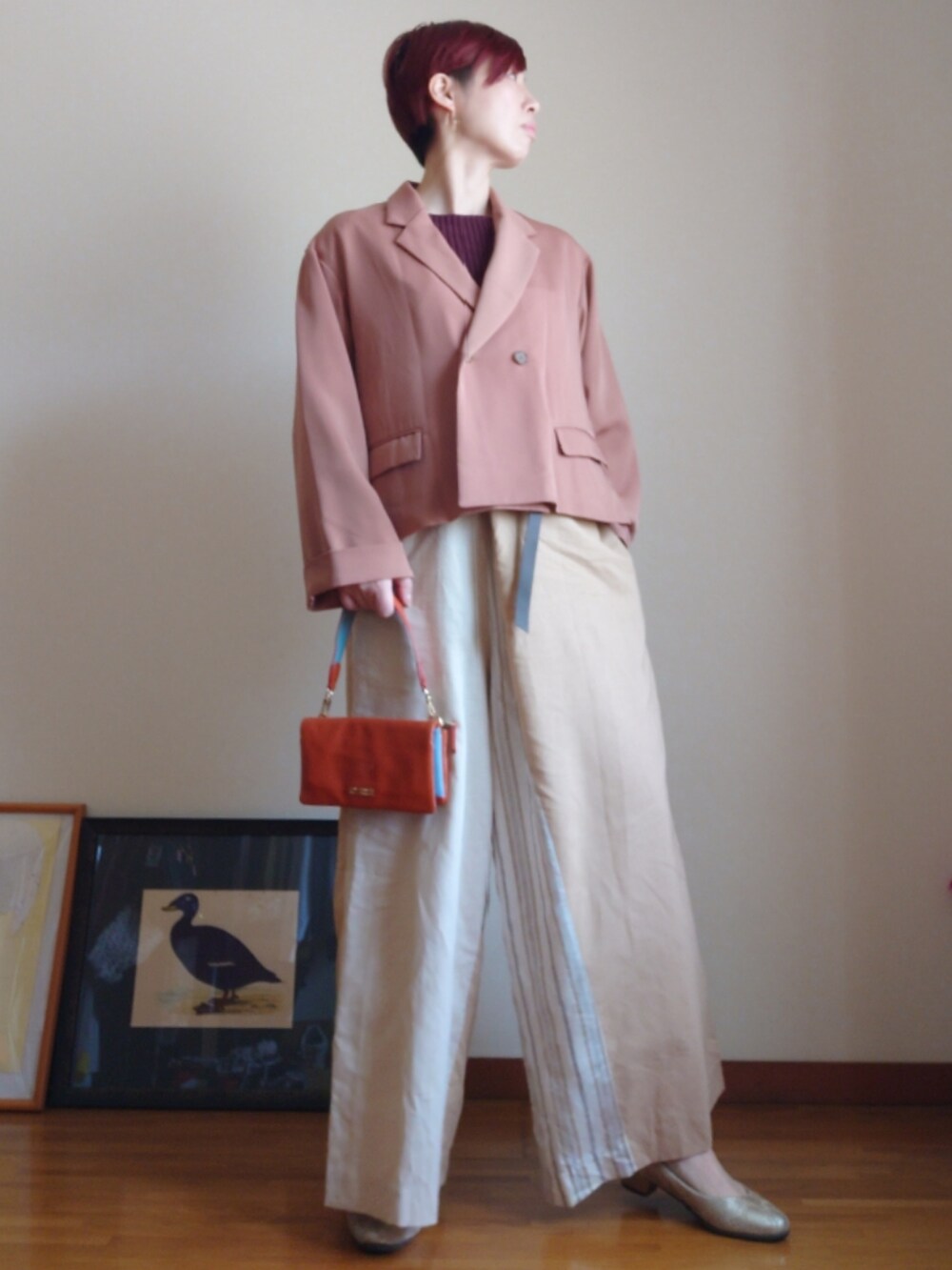 ベージュ系のパンツ、ブラウン系のTシャツ/カットソー、ピンク系のトレンチコートを着用したレディースの春コーディネートの2枚目の写真