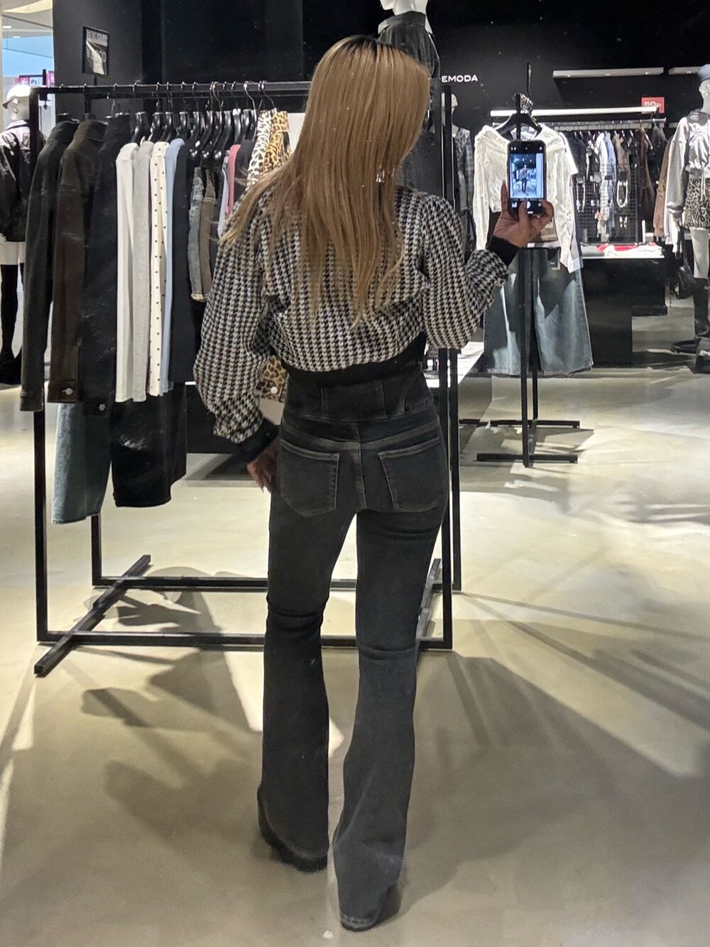 ブラック系のニット/セーター、ブルー系のデニムパンツ、ブラック系のブーツを着用したレディースの秋コーディネートの3枚目の写真