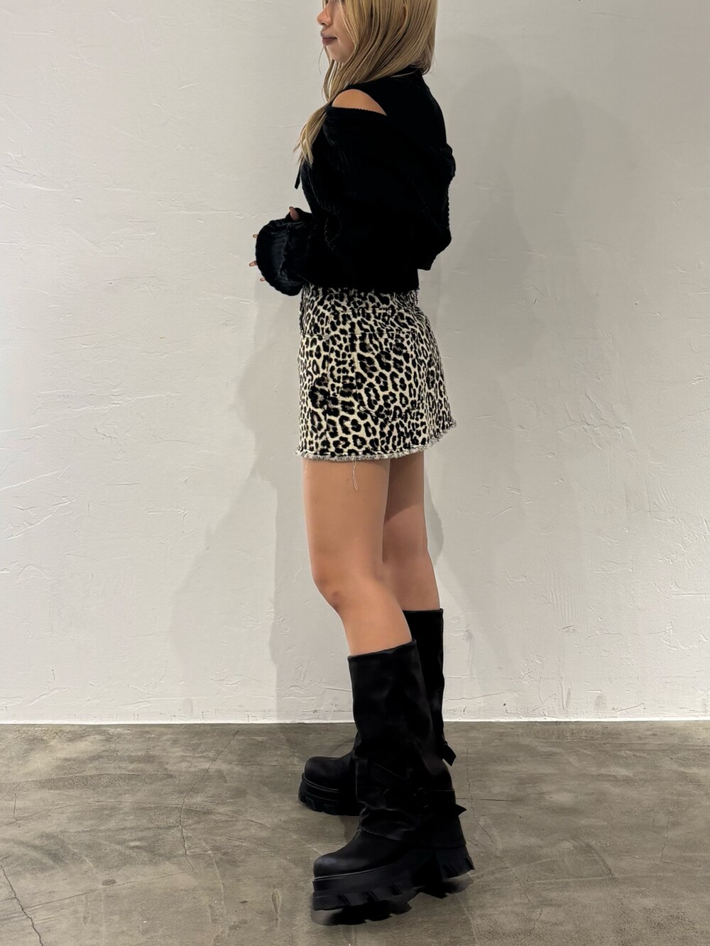 ホワイト系のスカート、ブラック系のニット/セーター、ブラック系のブーツを着用したレディースの秋コーディネートの2枚目の写真