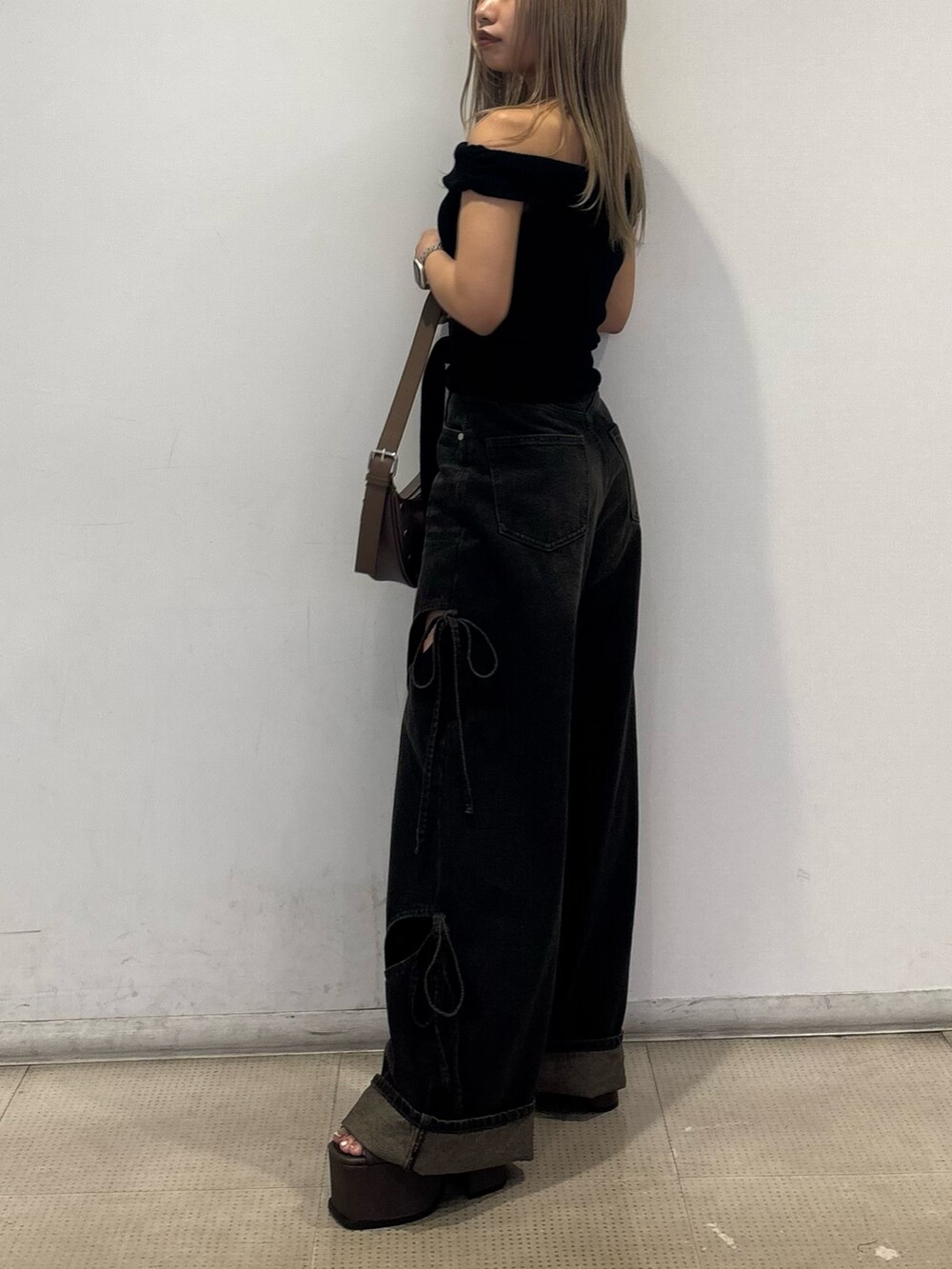 ブラック系のニット/セーター、ブラック系のデニムパンツ、ブラウン系のサンダルを着用したレディースの春コーディネートの2枚目の写真