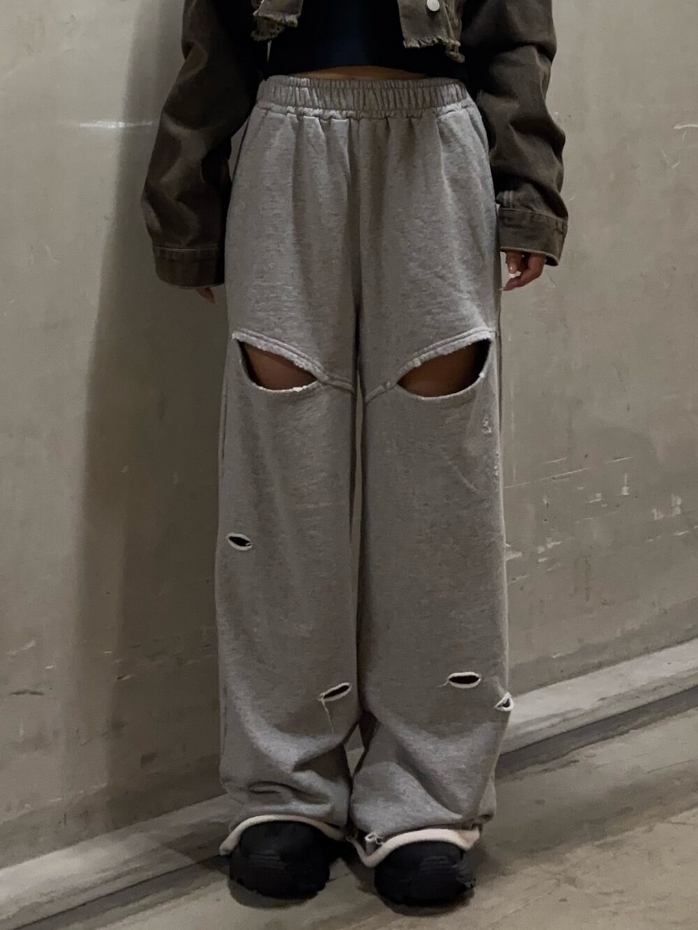 ブラウン系のデニムジャケット、グレー系のスウェットパンツ、ブラック系のスニーカーを着用したレディースの秋コーディネートの4枚目の写真