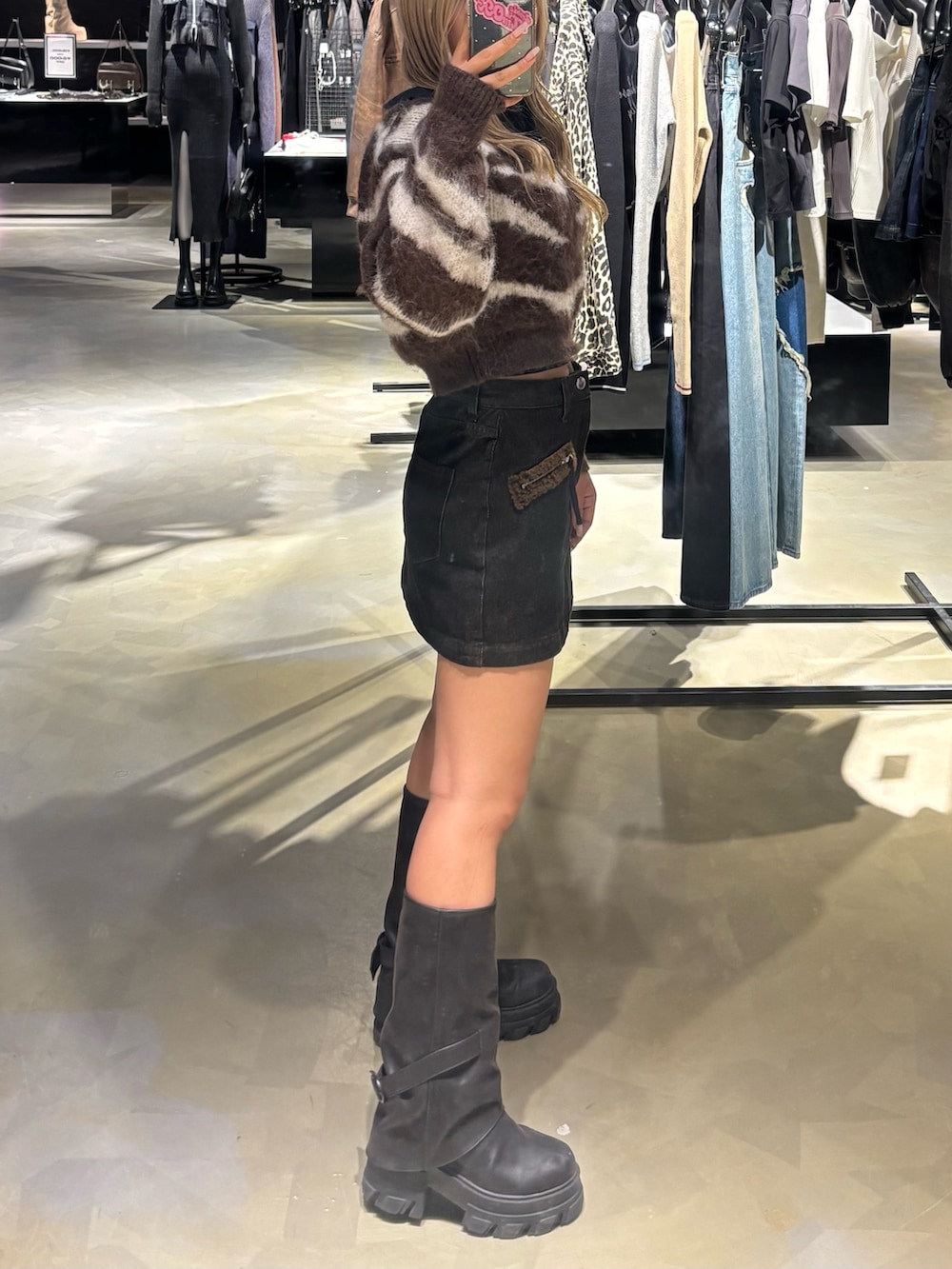 ブラウン系のニット/セーター、ブラック系のスカート、ブラック系のブーツを着用したレディースの秋コーディネートの2枚目の写真