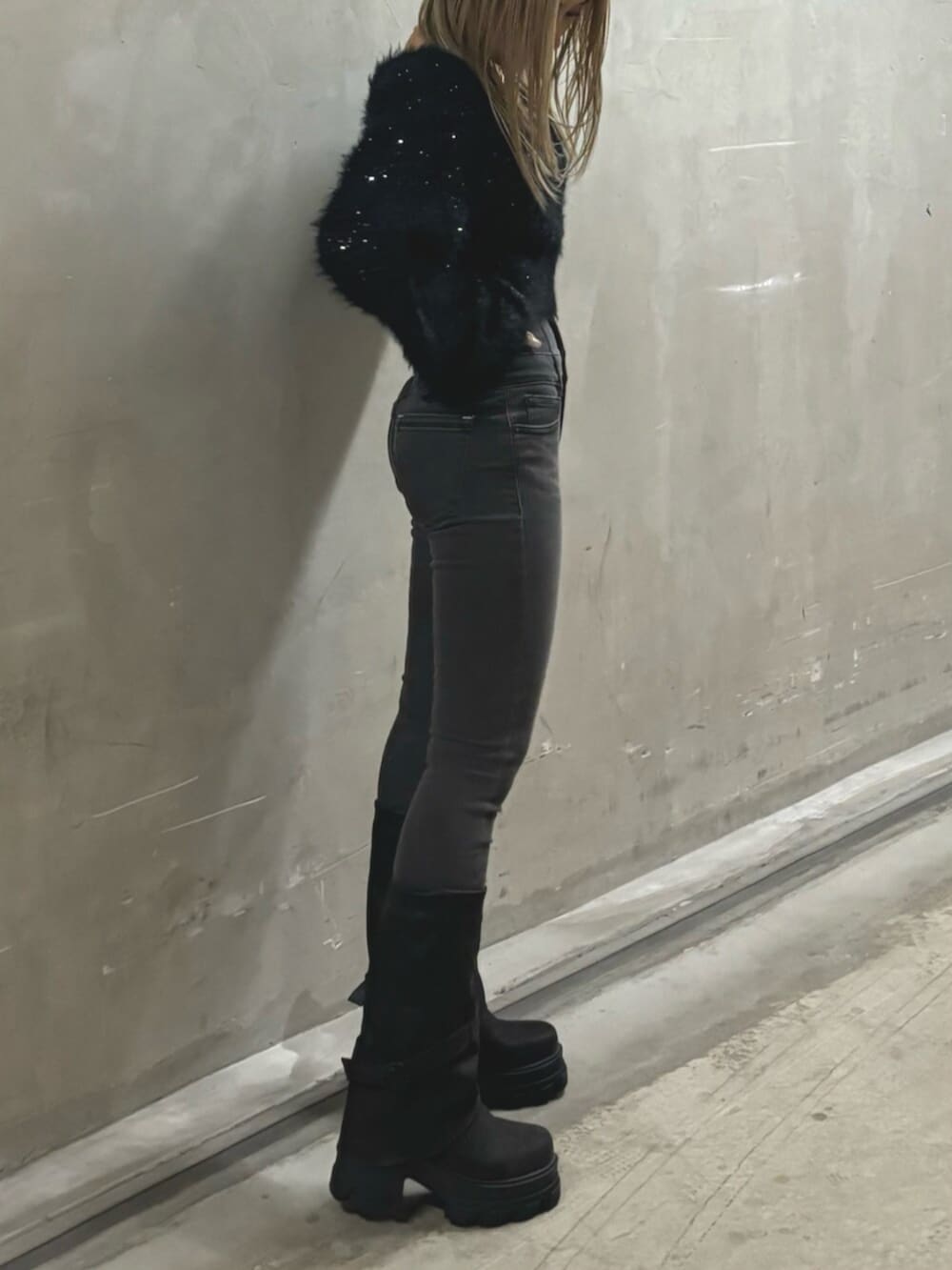 ブラック系のブーツ、ブラック系のニット/セーター、グレー系のデニムパンツを着用したレディースの冬コーディネートの2枚目の写真