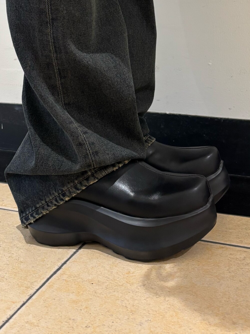 ブルー系のデニムパンツ、ブラック系のスリッポン、ブラック系のTシャツ/カットソーを着用したレディースの秋コーディネートの5枚目の写真