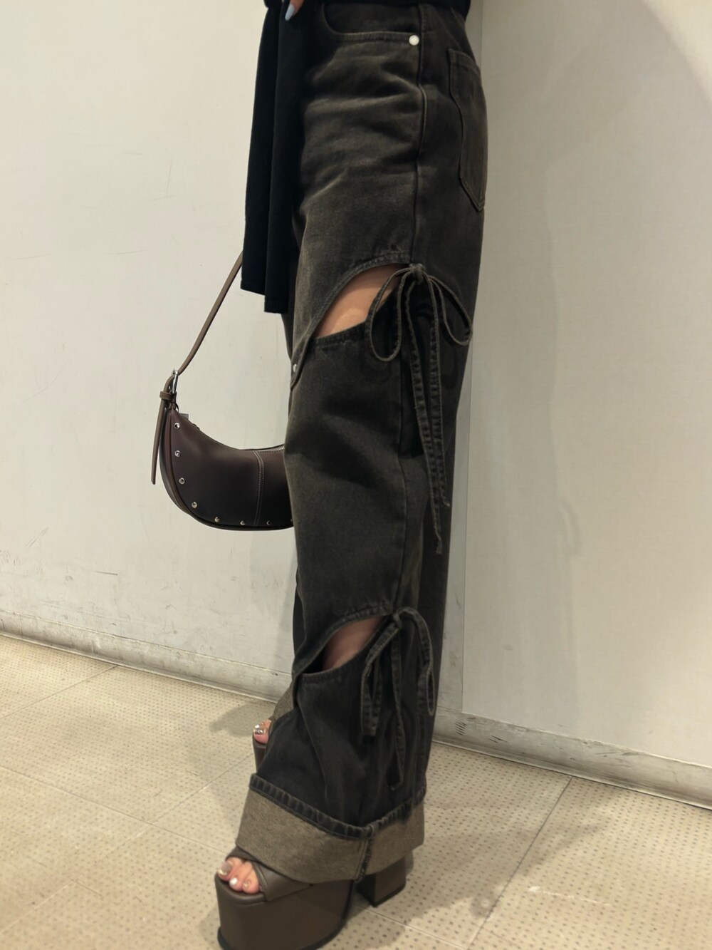 ブラック系のニット/セーター、ブラック系のデニムパンツ、ブラウン系のサンダルを着用したレディースの春コーディネートの5枚目の写真