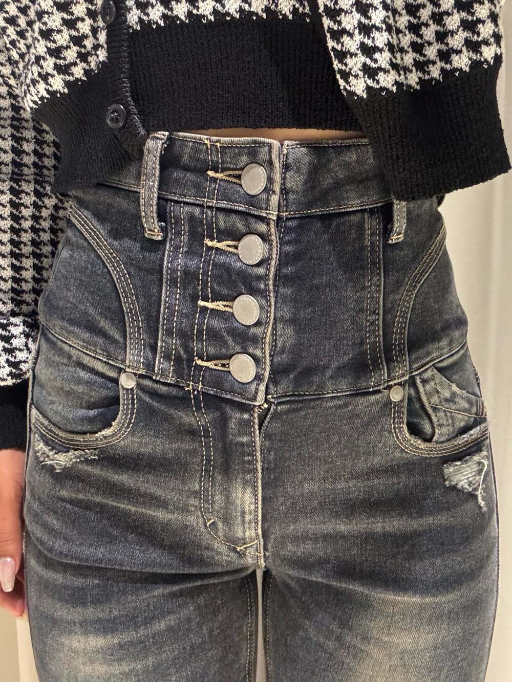 ブラック系のニット/セーター、ブルー系のデニムパンツ、ブラック系のブーツを着用したレディースの秋コーディネートの5枚目の写真