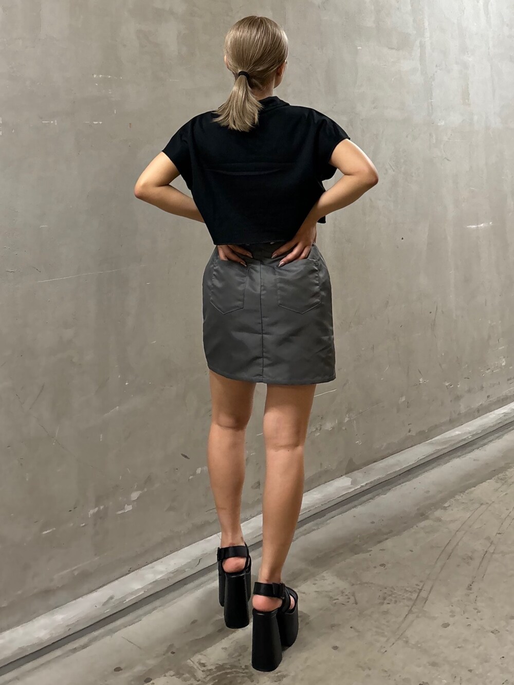 グレー系のスカート、ブラック系のTシャツ/カットソー、ブラック系のサンダルを着用したレディースの夏コーディネートの3枚目の写真