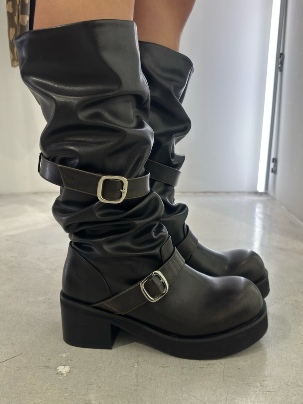 グレー系のパーカー、グレー系のスカート、ブラック系のブーツを着用したレディースの冬コーディネートの5枚目の写真