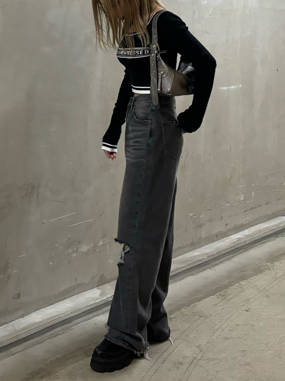 グレー系のデニムパンツ、ブラック系のニット/セーター、シルバー系のハンドバッグを着用したレディースの秋コーディネートの2枚目の写真