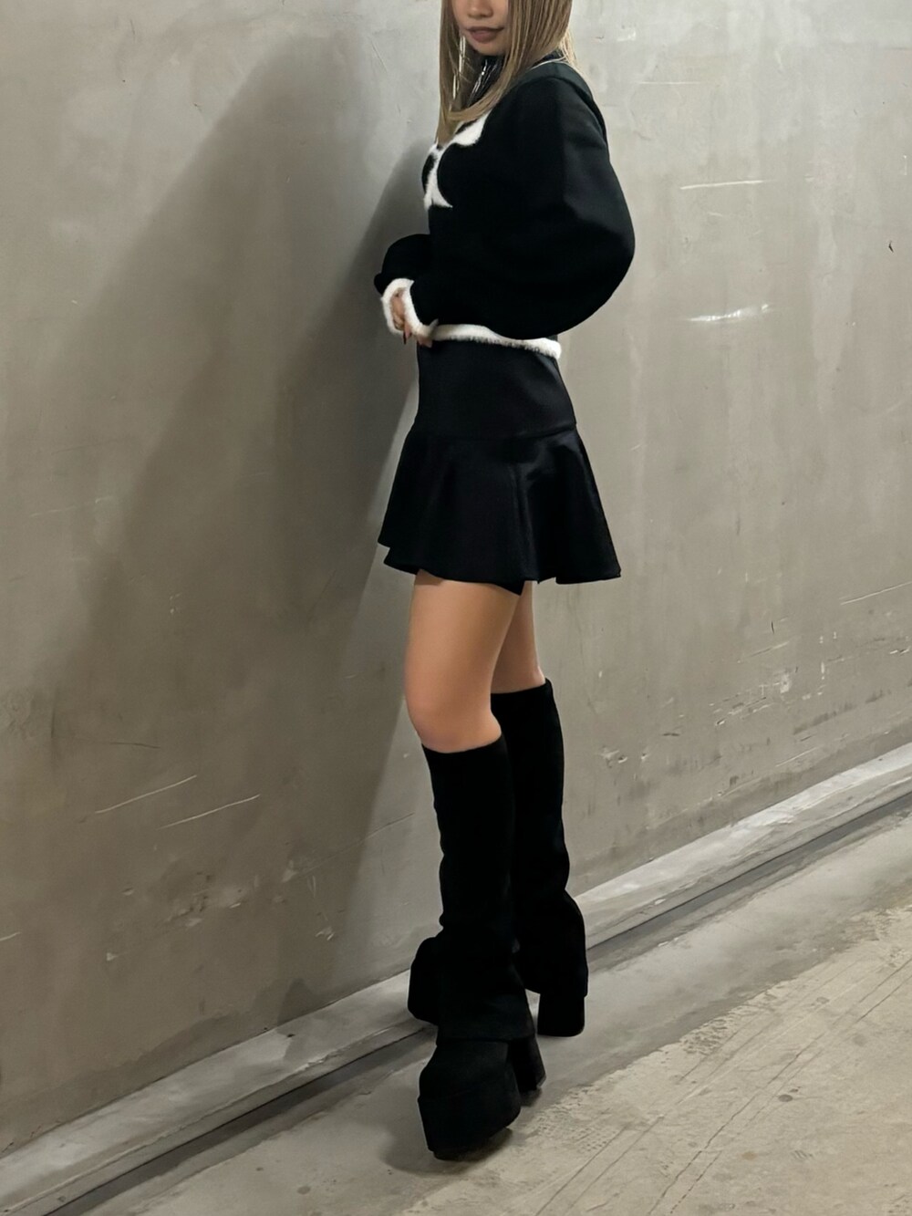 ブラック系のニット/セーター、ブラック系のスカート、ブラック系のブーツを着用したレディースの冬コーディネートの2枚目の写真