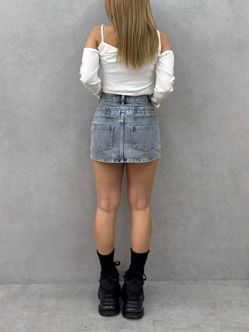 ブラック系のスニーカー、ホワイト系のTシャツ/カットソー、ブルー系のスカートを着用したレディースの春コーディネートの3枚目の写真