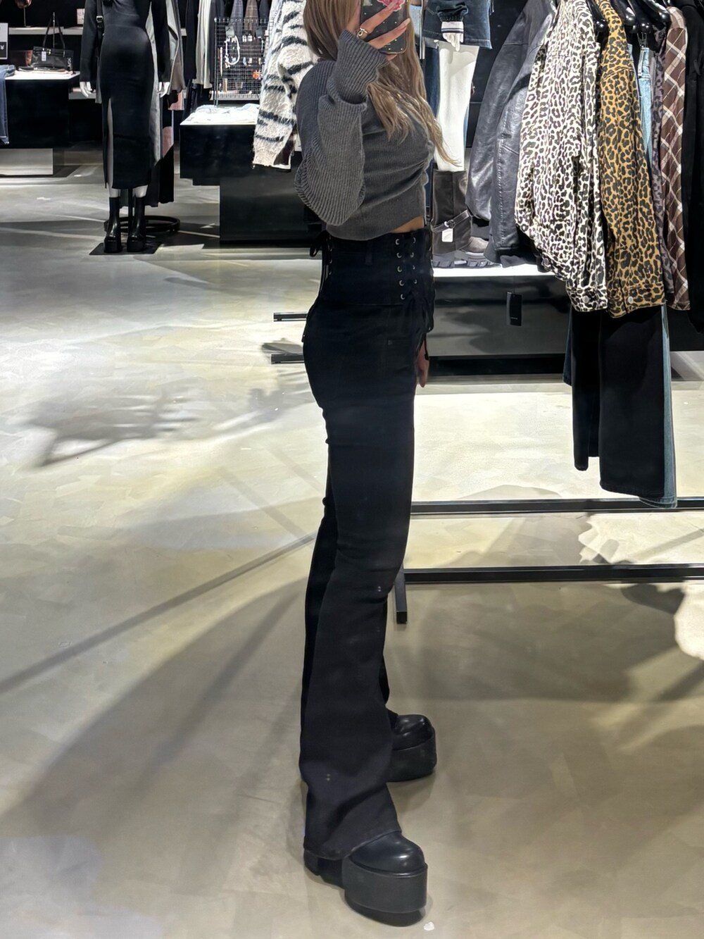 ブラック系のデニムパンツ、ブラック系のブーツ、グレー系のニット/セーターを着用したレディースの冬コーディネートの2枚目の写真