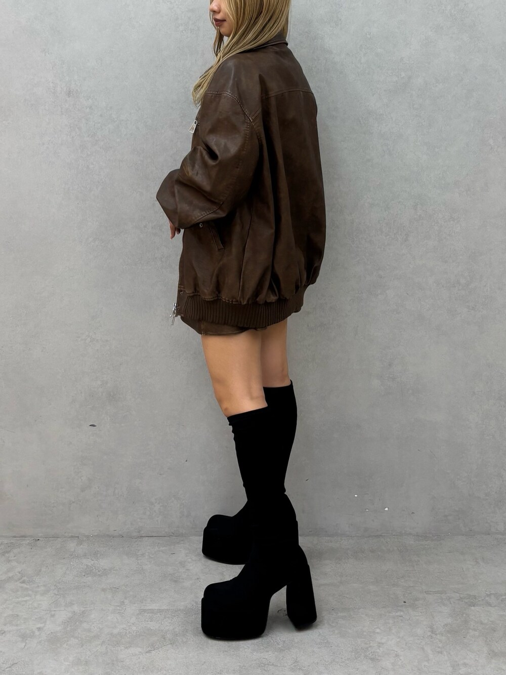 ブラック系のニット/セーター、ブラウン系のブルゾン、ブラック系のブーツを着用したレディースの秋コーディネートの2枚目の写真