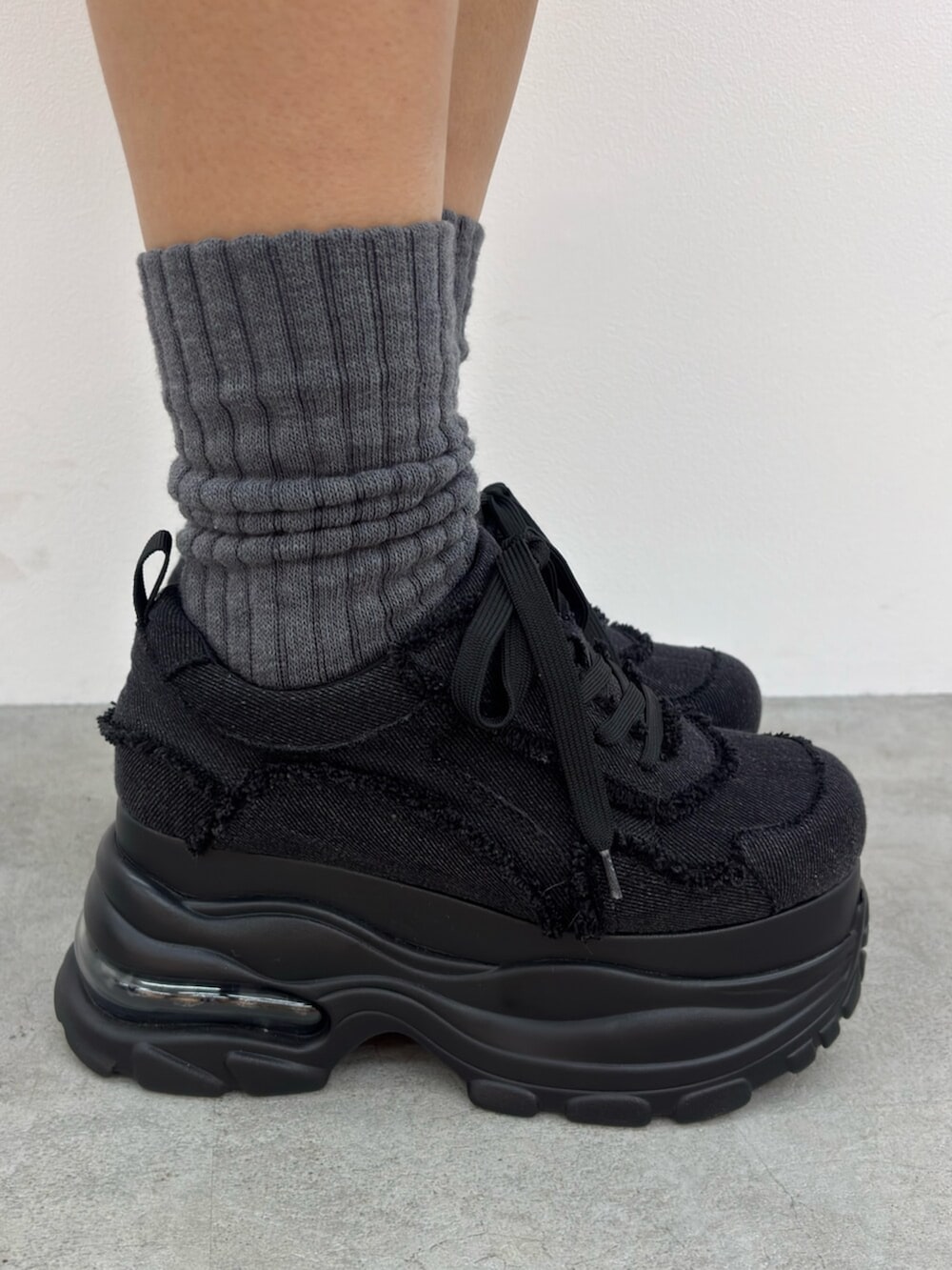 ブラック系のスニーカー、ホワイト系のTシャツ/カットソー、ブルー系のスカートを着用したレディースの春コーディネートの5枚目の写真