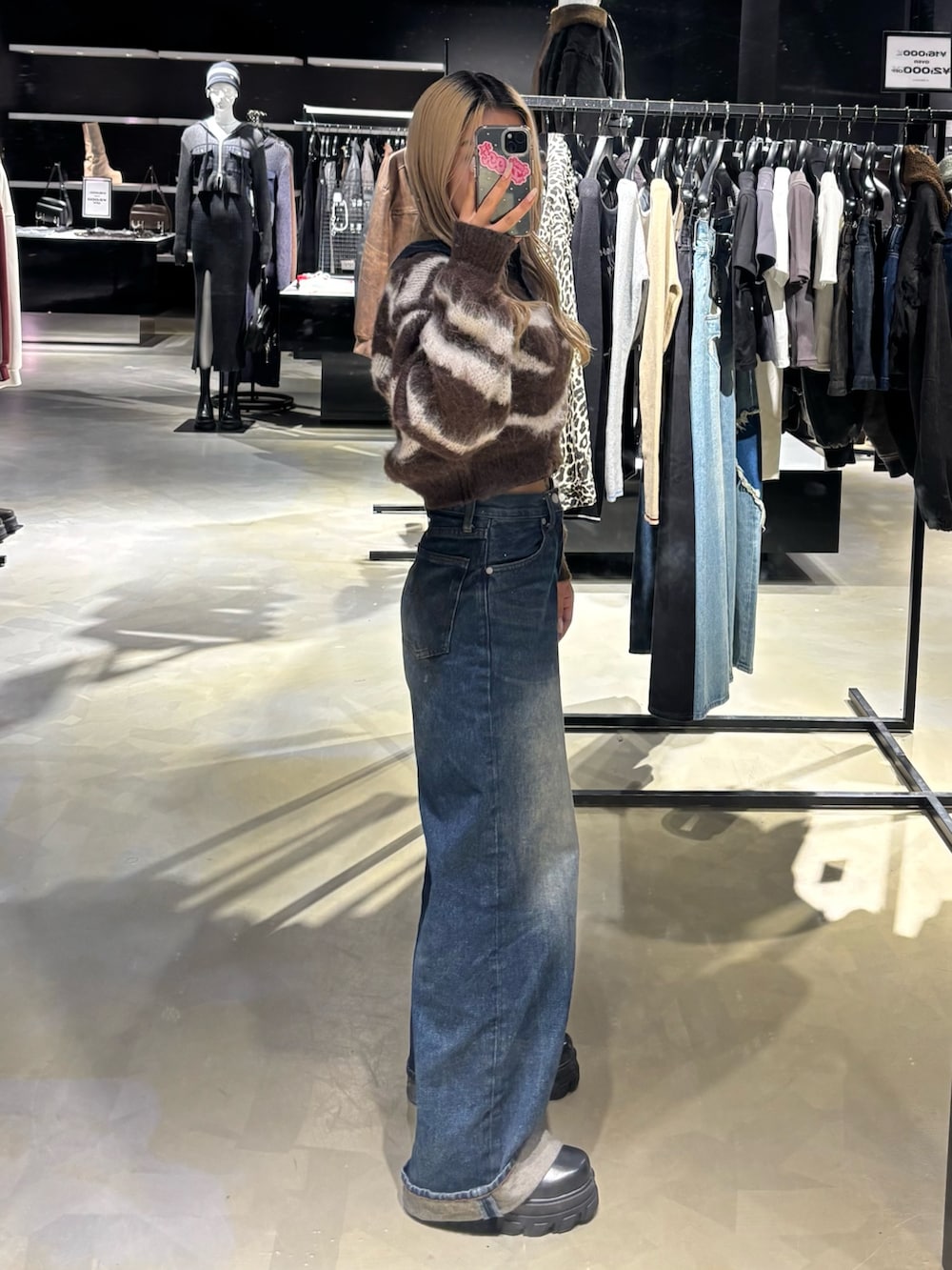 ブラウン系のニット/セーター、ブルー系のデニムパンツ、ブラック系のブーツを着用したレディースの秋コーディネートの2枚目の写真