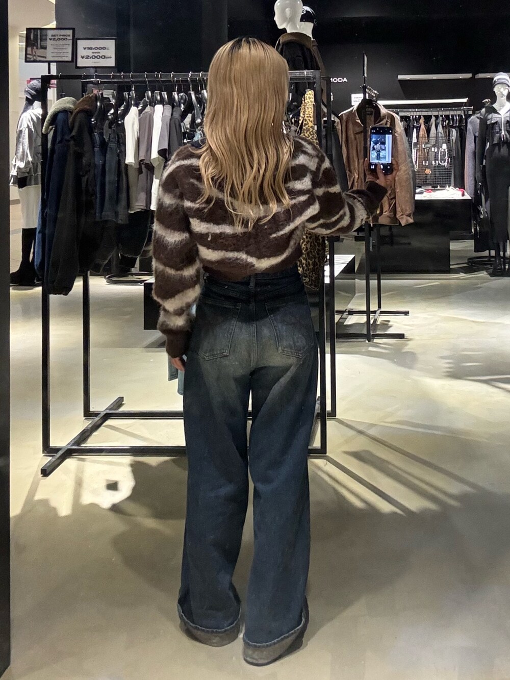 ブラウン系のニット/セーター、ブルー系のデニムパンツ、ブラック系のブーツを着用したレディースの秋コーディネートの3枚目の写真