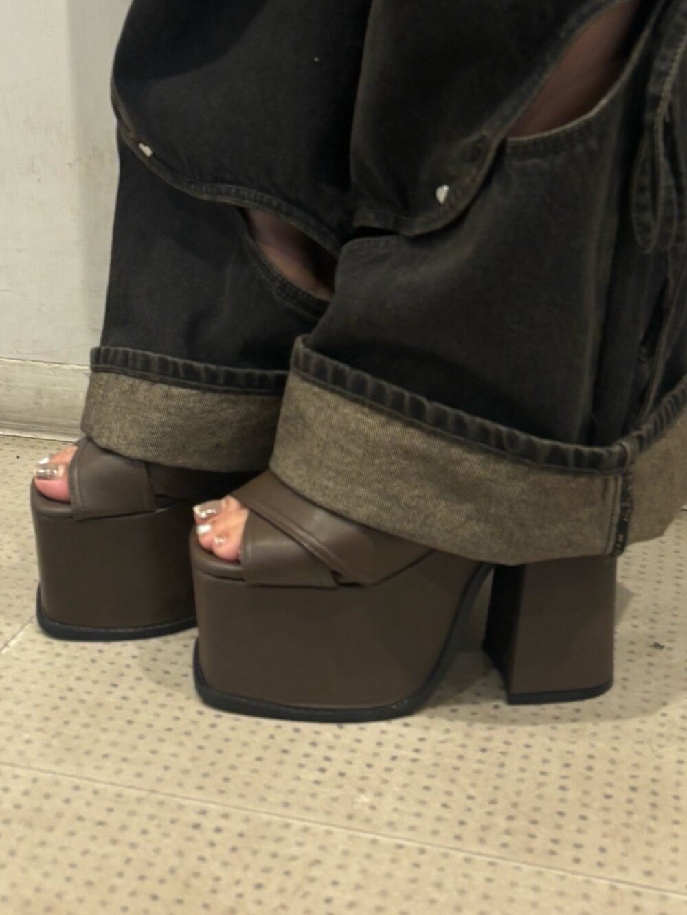 ブラック系のニット/セーター、ブラック系のデニムパンツ、ブラウン系のサンダルを着用したレディースの春コーディネートの6枚目の写真