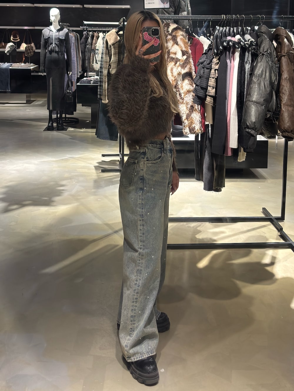 ブラウン系のニット/セーター、ブルー系のデニムパンツ、ブラック系のブーツを着用したレディースの冬コーディネートの2枚目の写真