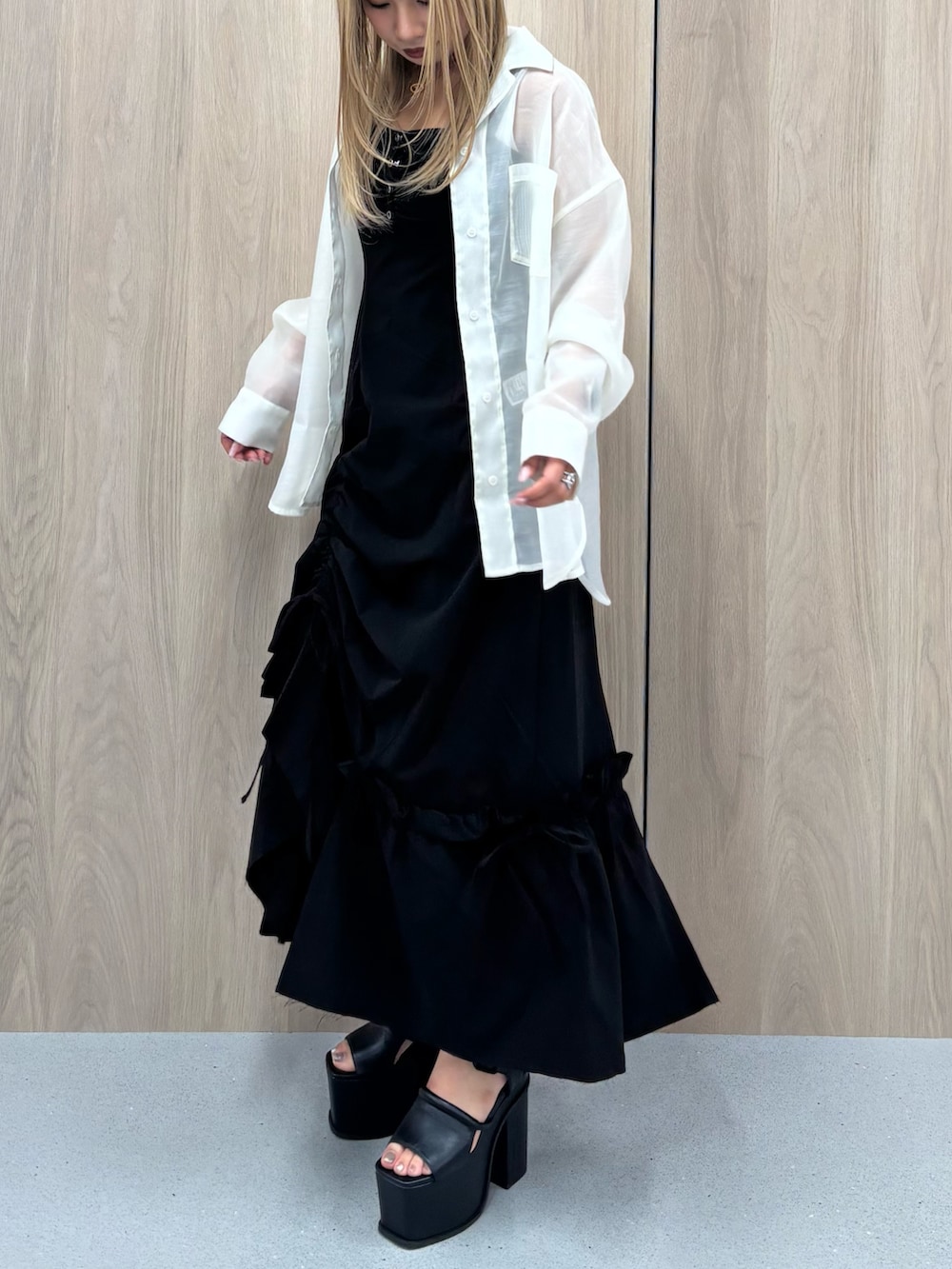 ブラック系のワンピース、ホワイト系のシャツ/ブラウス、ブラック系のサンダルを着用したレディースの春コーディネートの2枚目の写真