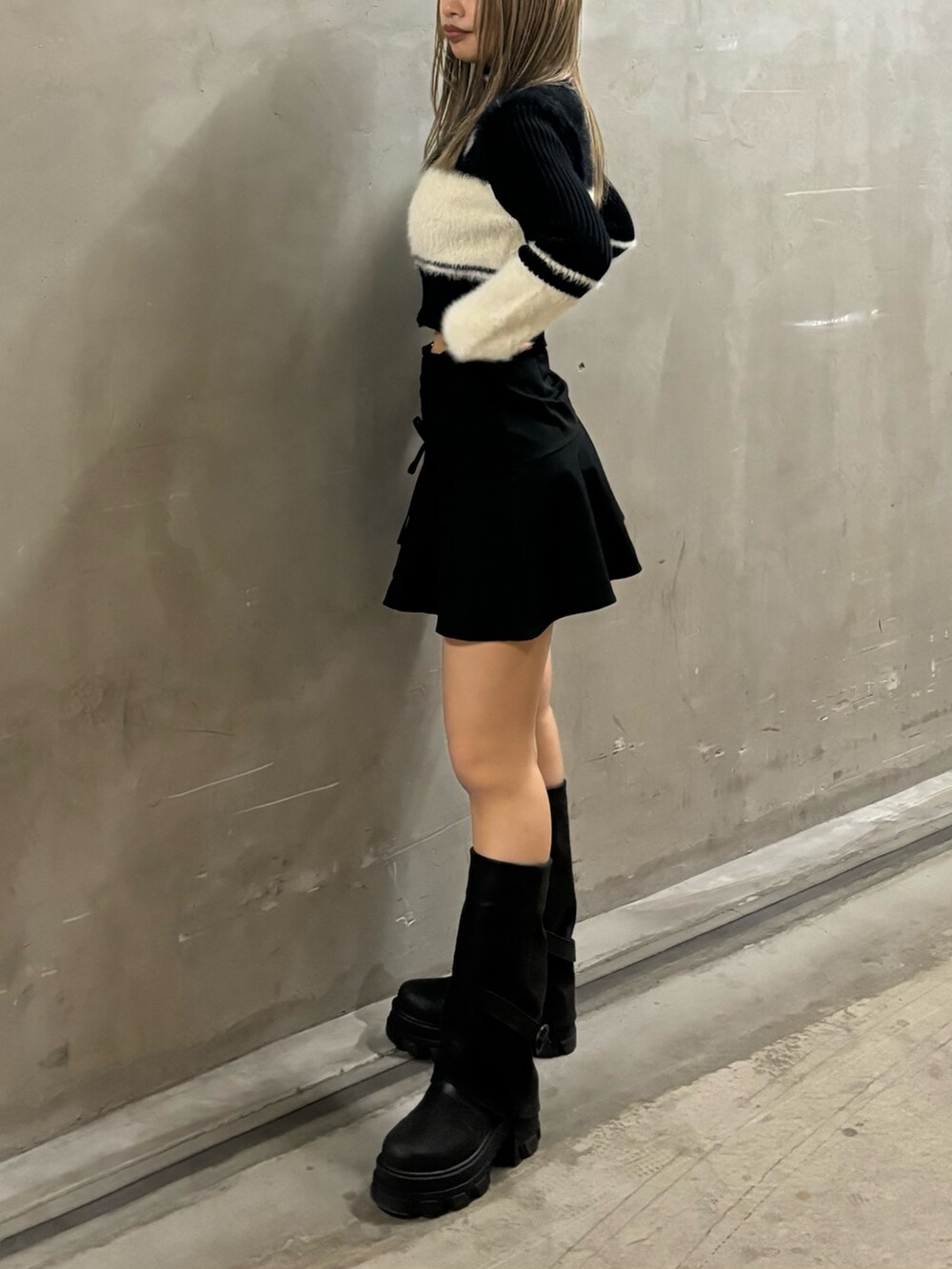 ブラック系のニット/セーター、ブラック系のスカート、ブラック系のブーツを着用したレディースの冬コーディネートの2枚目の写真