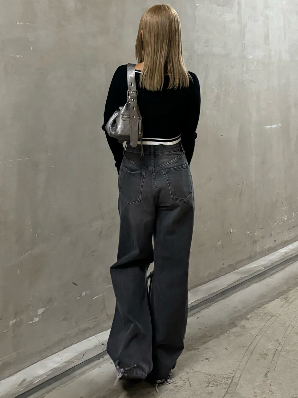 グレー系のデニムパンツ、ブラック系のニット/セーター、シルバー系のハンドバッグを着用したレディースの秋コーディネートの3枚目の写真